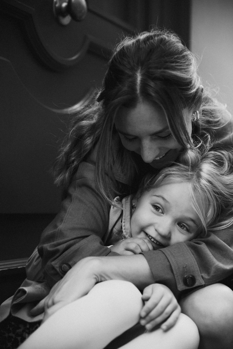 Black and white: a mother hugs her laughing daughter from behind