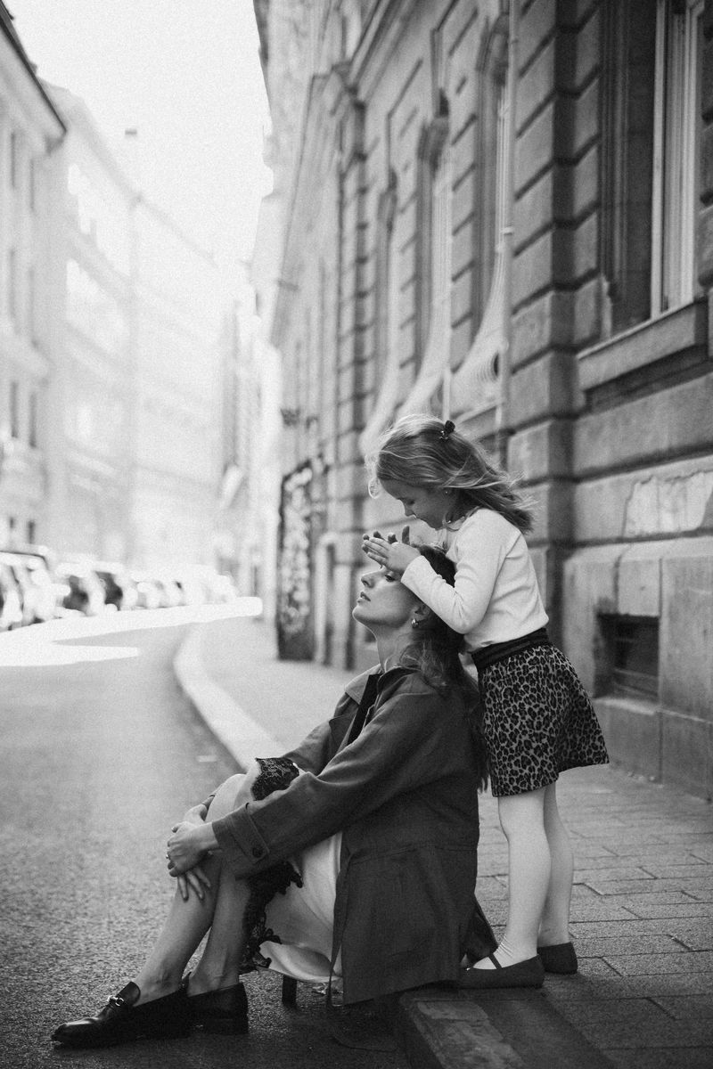 Black and white: a girl kisses her mother's forehead on a city street