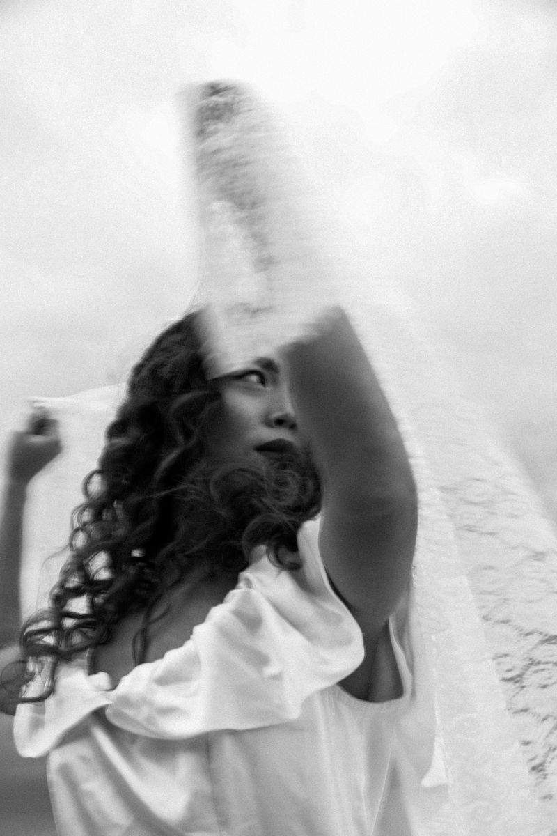 Black and white: a woman in a white dress, a veil lifted by the wind