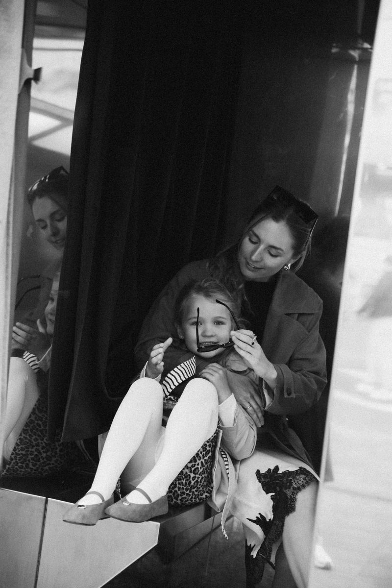 Black and white: mother and daughter sitting in a doorway, the girl laughing