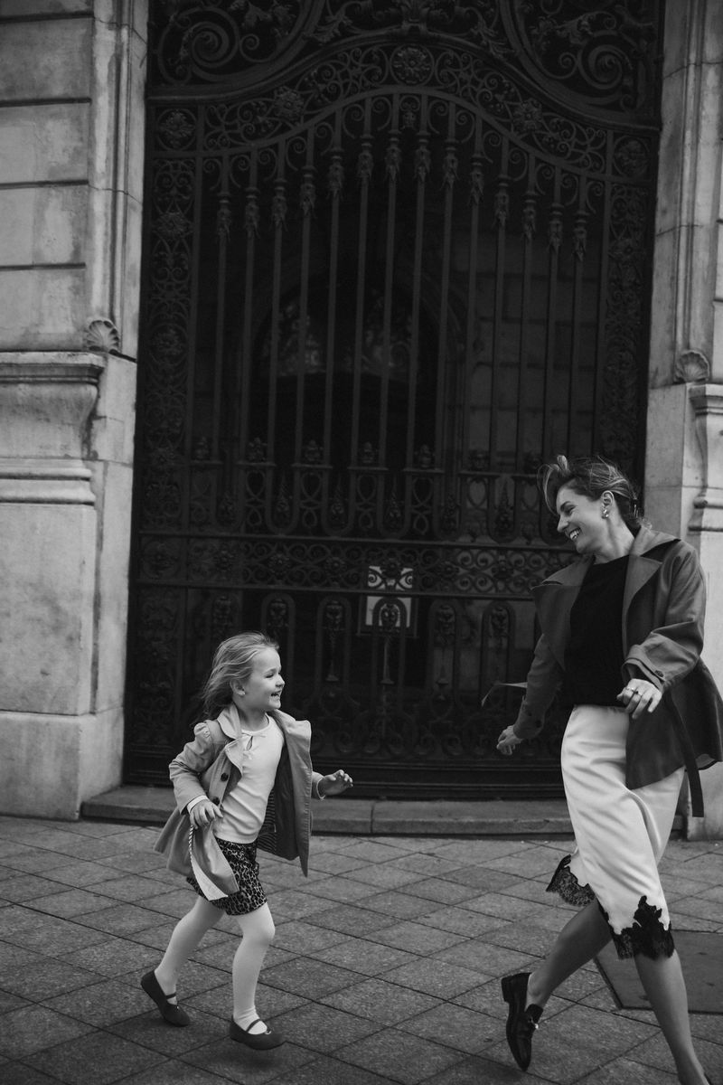 Black and white: mother and daughter running toward each other by an iron gate