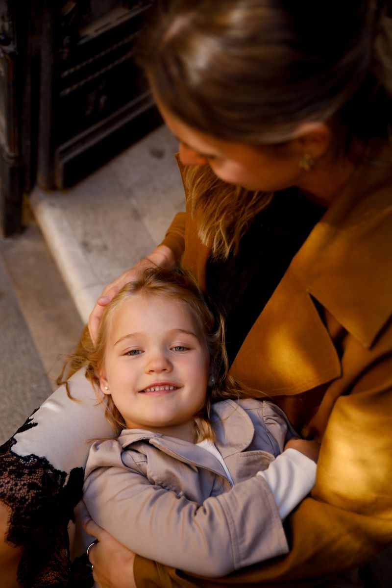 A smiling girl lying in her mother's lap in warm light