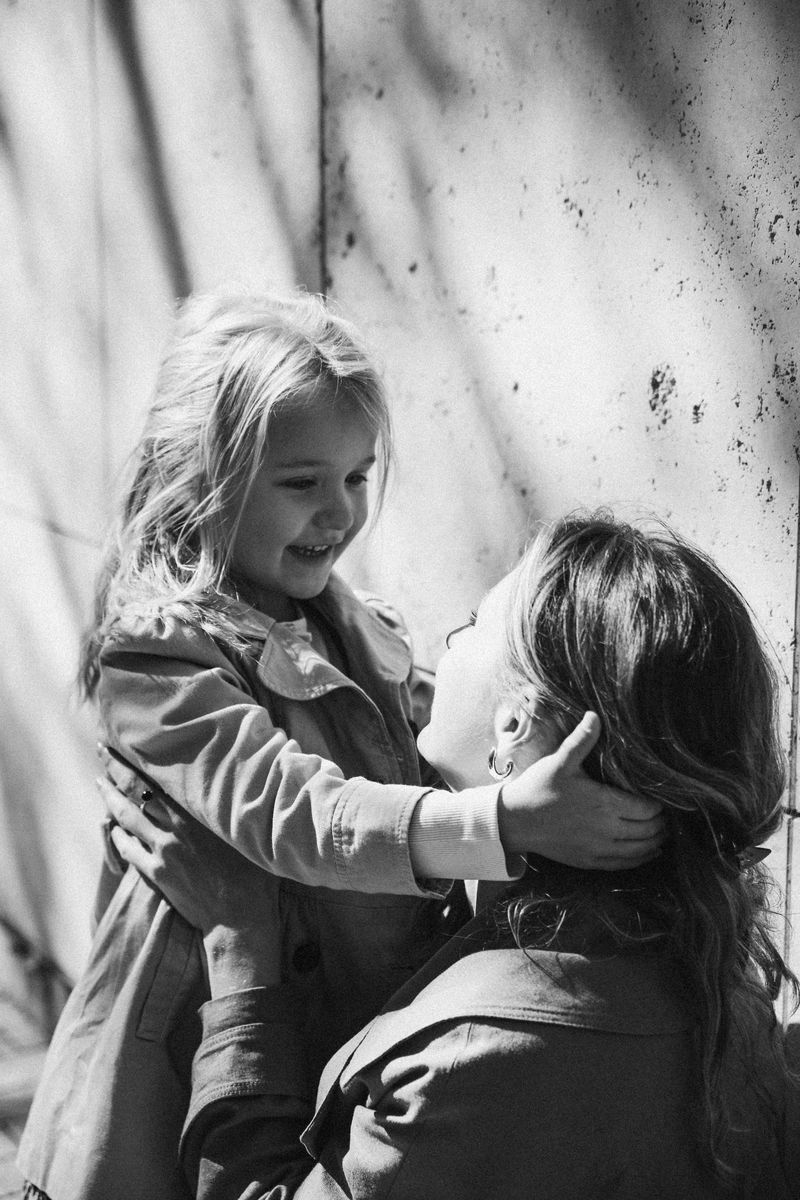 Black and white: a girl holds her mother's face in her hands