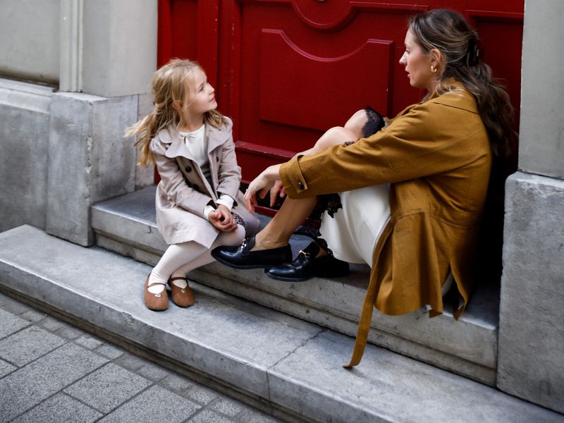 Mother and daughter talking on the steps of a red door